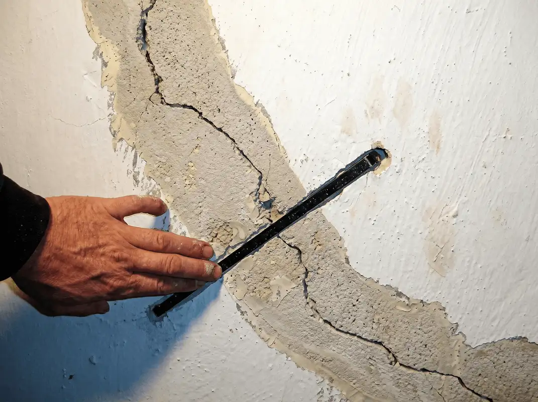 A wall with a large crack is being inspected by a professional in Long Beach, CA